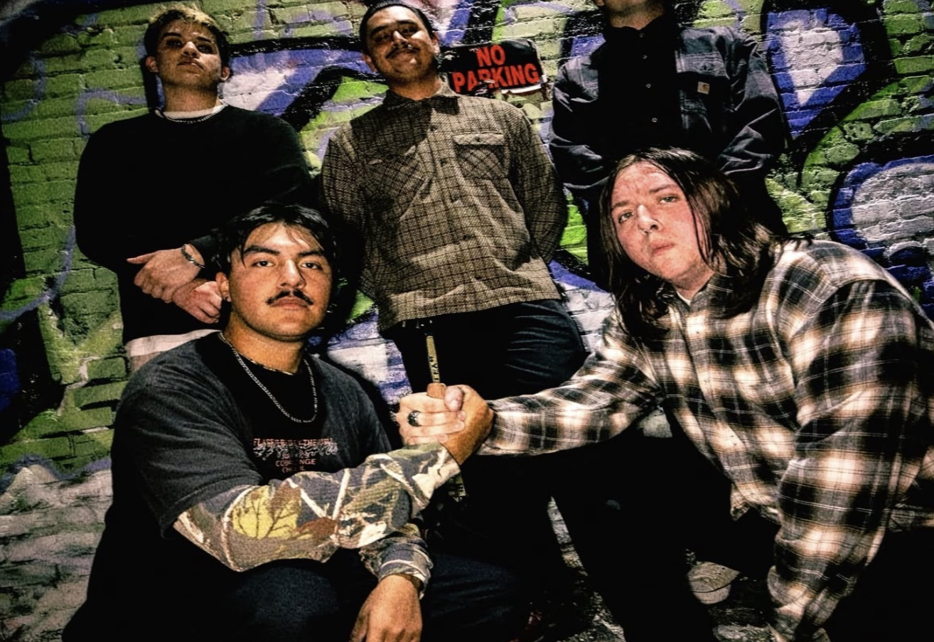 5 member band pose in front of graffiti wall