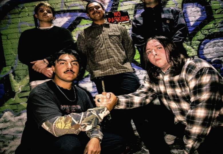5 member band pose in front of graffiti wall